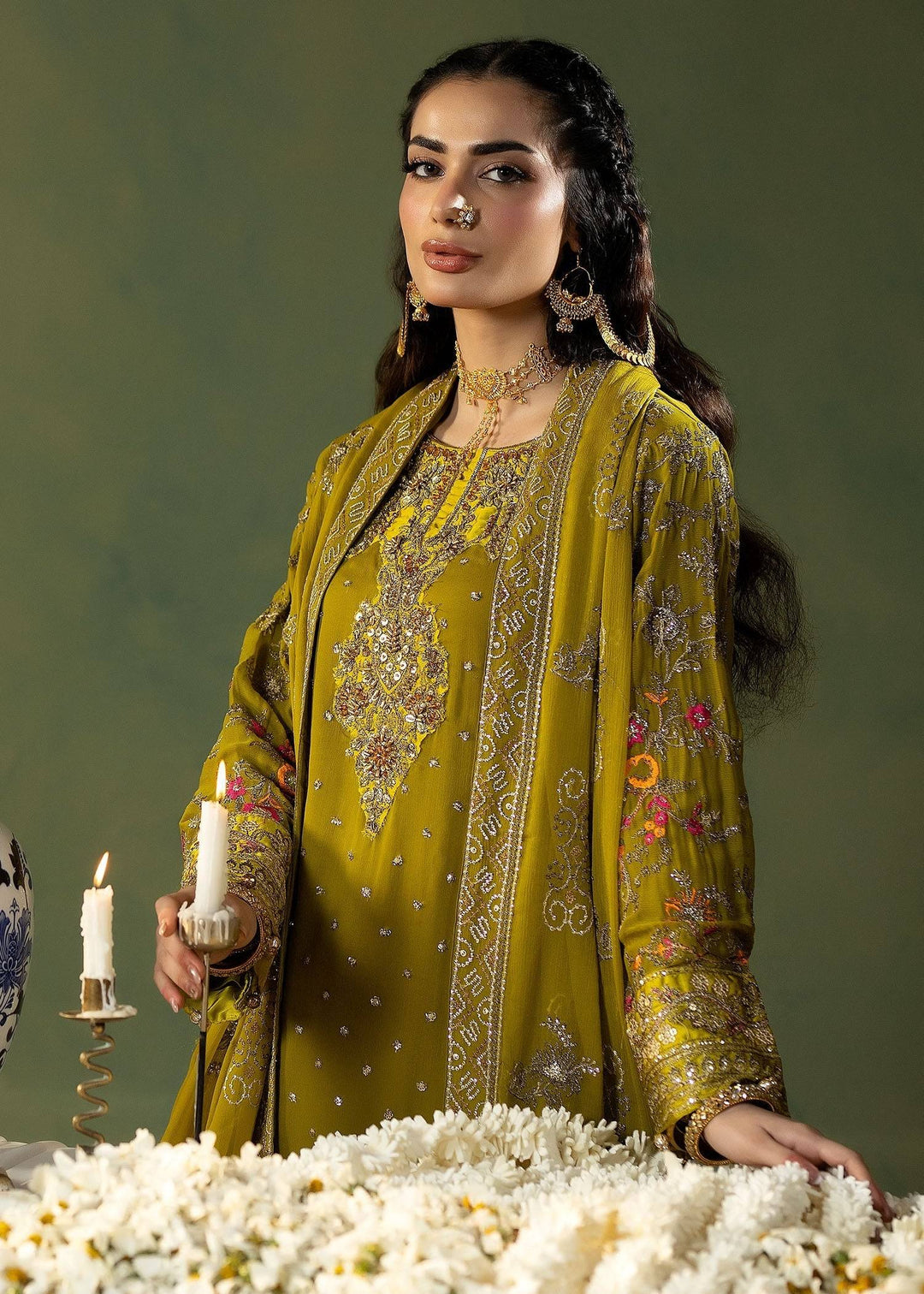 Model wearing RANGREZA OLIVE | M-908-13 holding candle, featuring detailed embroidery on chiffon shirt and dupatta with festive accessories.