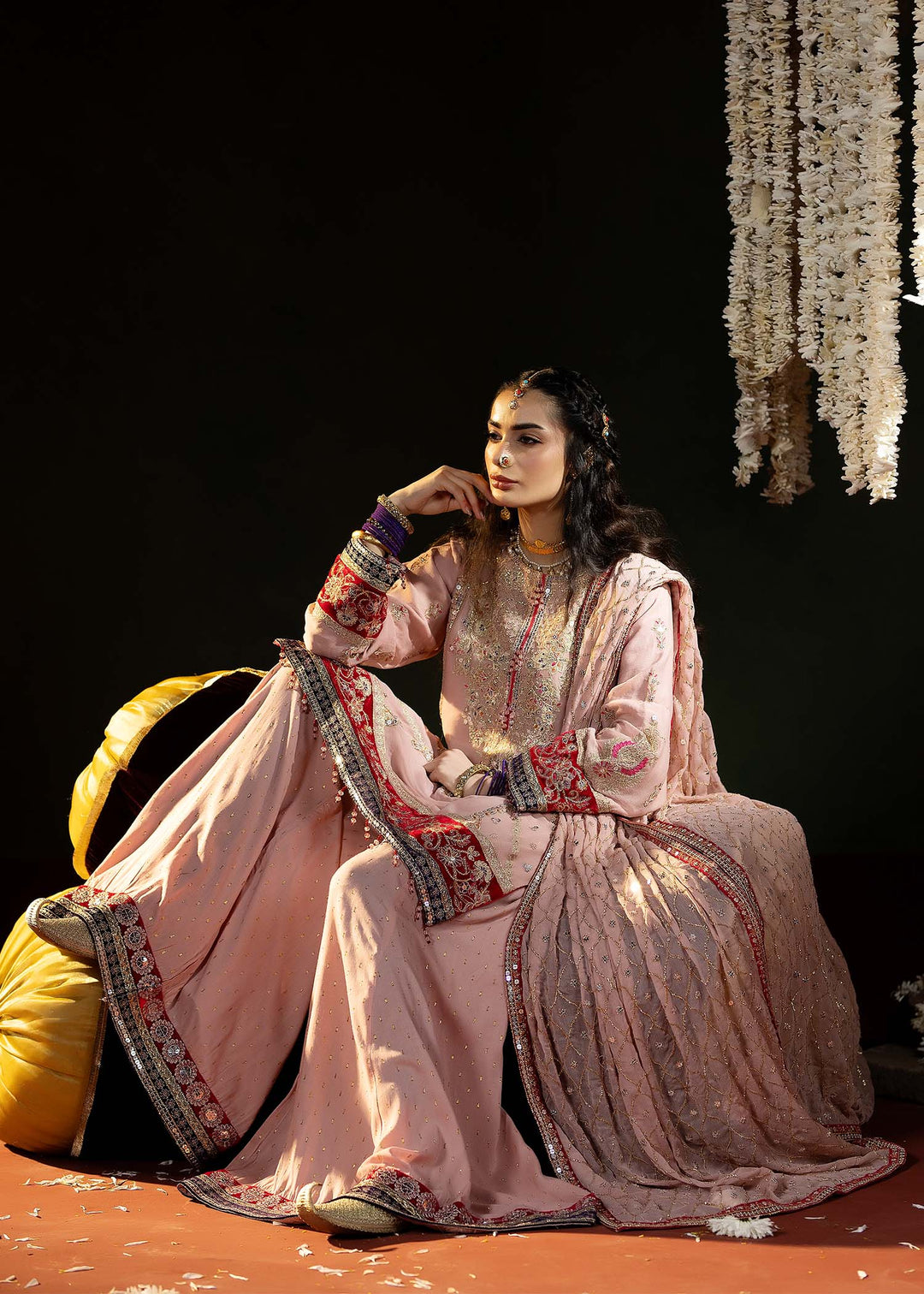 Model seated in RANGREZA PINK chiffon shirt and dupatta ensemble, featuring velvet borders and festive embroidery for South Asian fashion.