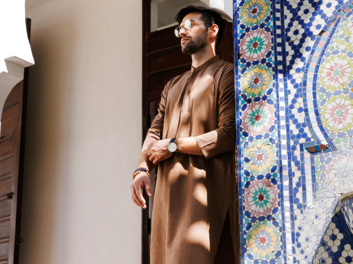 Man in brown kurta with sunglasses near colorful mosaic wall