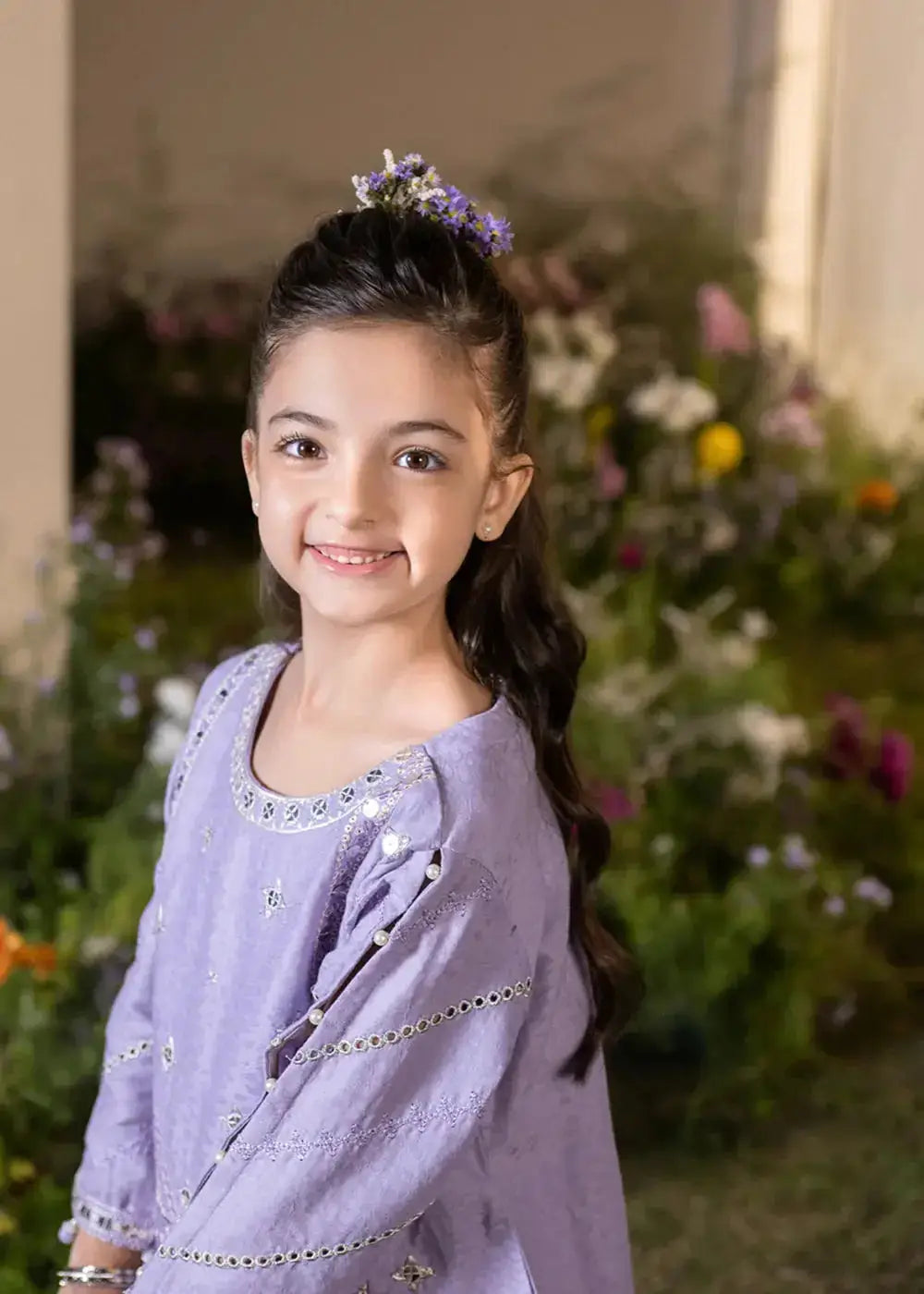Child in lavender embroidered kurta with floral accessories, festive apparel