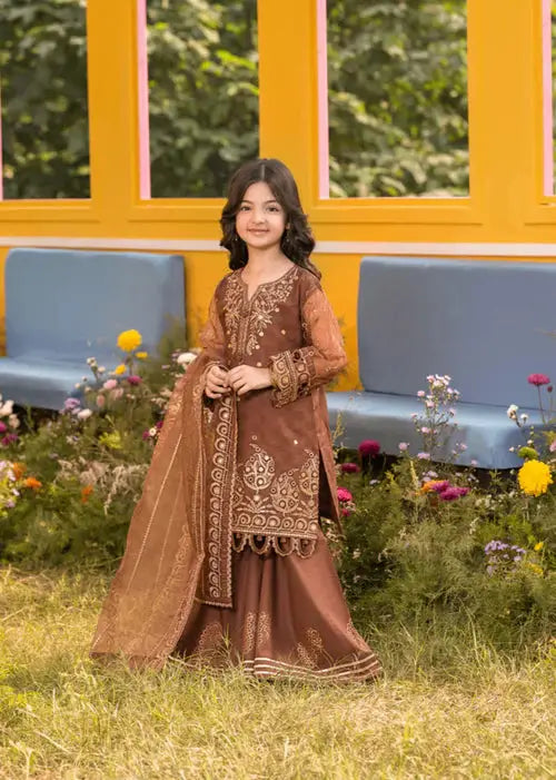 Girl in brown traditional outfit with dupatta, posing in floral garden with yellow wall backdrop