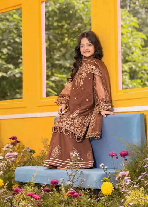 Girl sitting on blue bench in brown embroidered outfit with dupatta, colorful garden setting