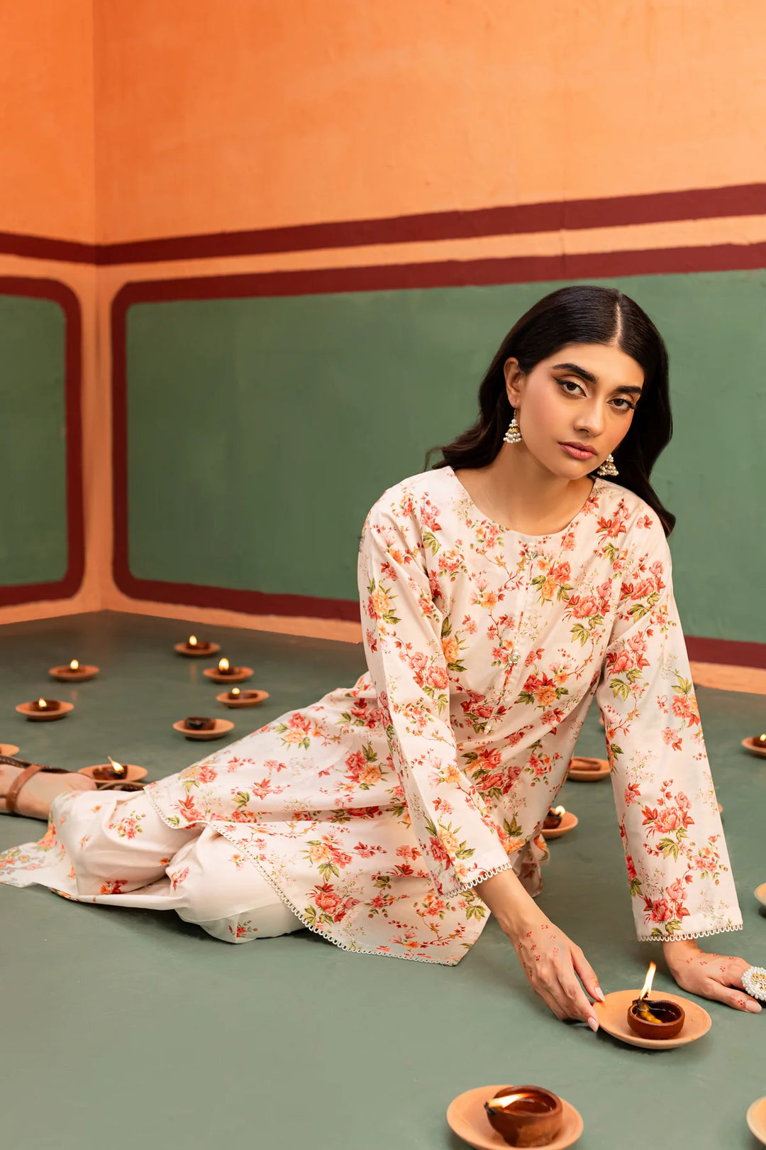 a BATIK READY TO WEAR woman sitting on the floor with a plate of food