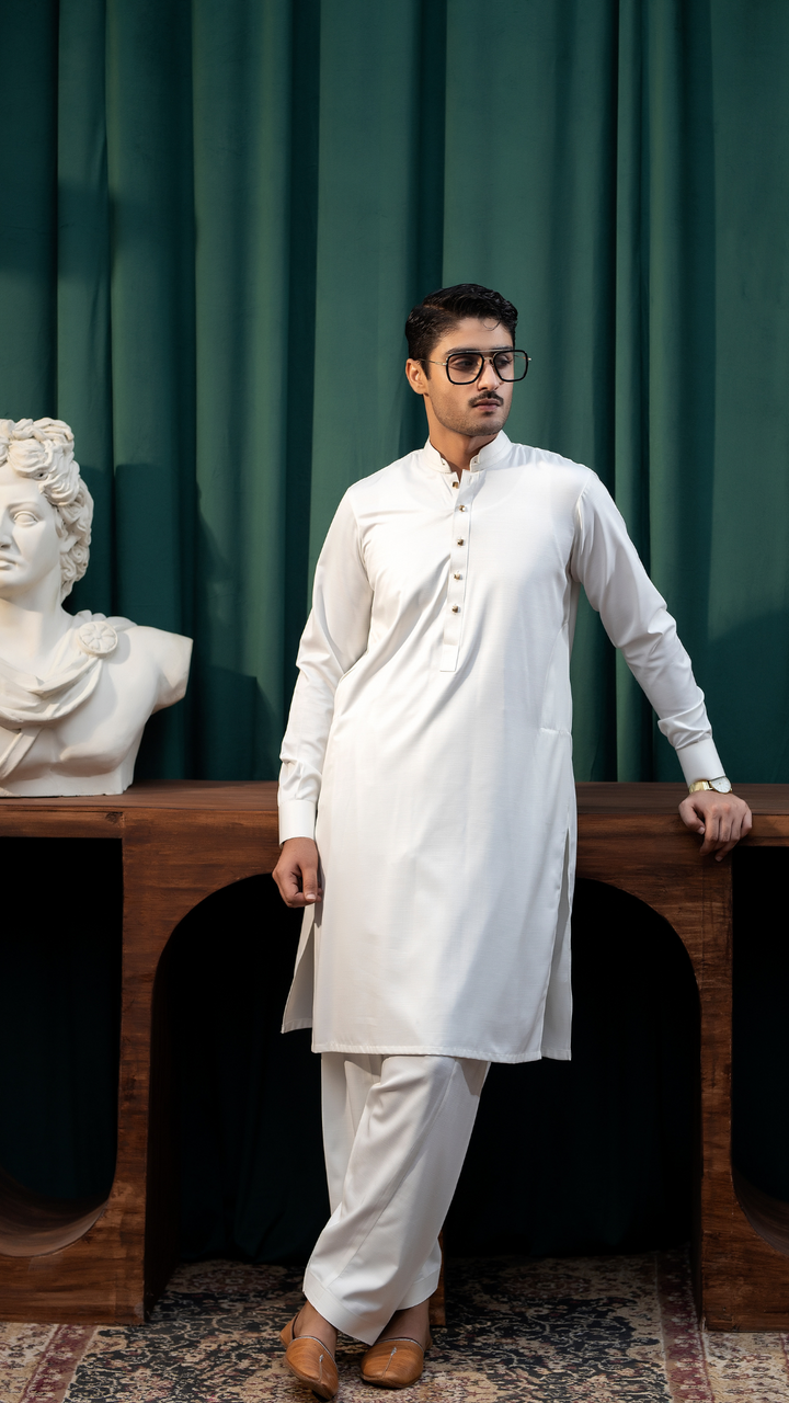 White traditional men's kurta pajama by Rangreza, featuring a sleek design with buttoned neckline, styled with brown loafers.