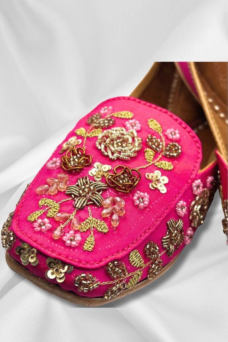 Close-up of Aafreen Pink Jutti showcasing detailed gold threadwork and bead embellishments on rich fuchsia fabric for ethnic elegance.