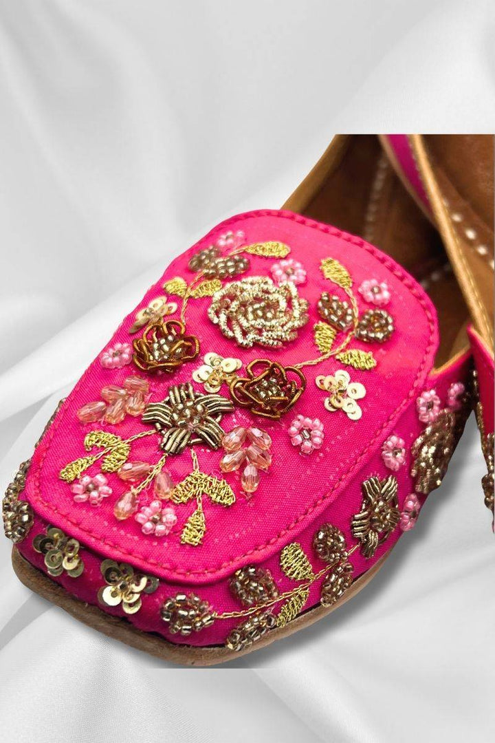 Close-up of Aafreen Pink Jutti showcasing detailed gold threadwork and bead embellishments on rich fuchsia fabric for ethnic elegance.