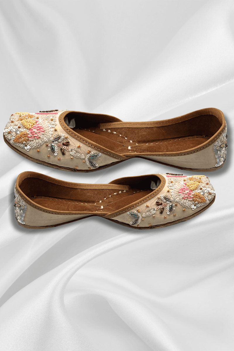 Side view of beige khussa flats featuring colorful floral threadwork and bead embellishments, perfect for ethnic and resort outfits.