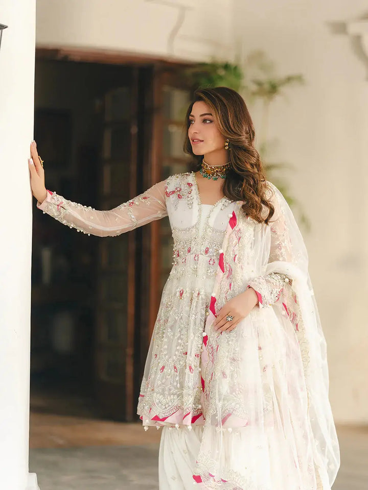 Net fabric peplum with sequin embroidery, hand-composed adda work, naqshi, dabka, pearls, crystals, chainwork, lace, and paranda tassels, paired with a net dupatta with spangle embroidery, pearls, gotta patti, and beads, in a traditional white and pink design for wedding attire