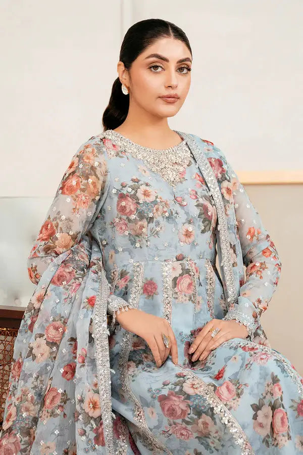 Seated model wearing BAROOQUE Printed Chiffon Kalidar Frock with shimmering embellishments and floral motifs on soft blue fabric.