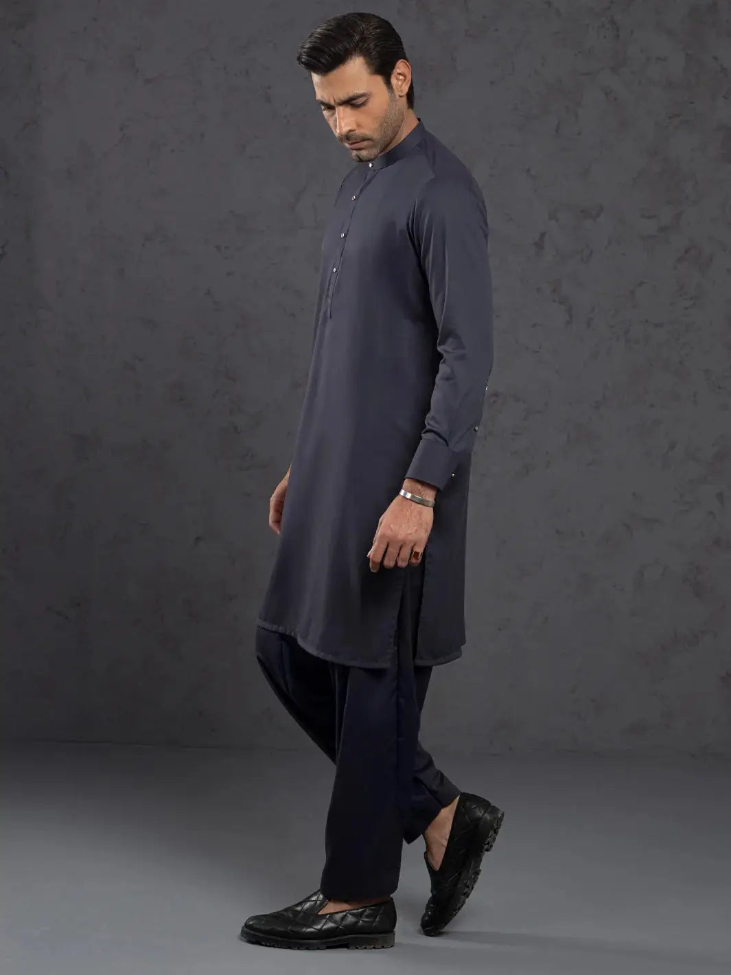 Man in navy blue kurta with mandarin collar and button placket, side view showing fit and fabric details