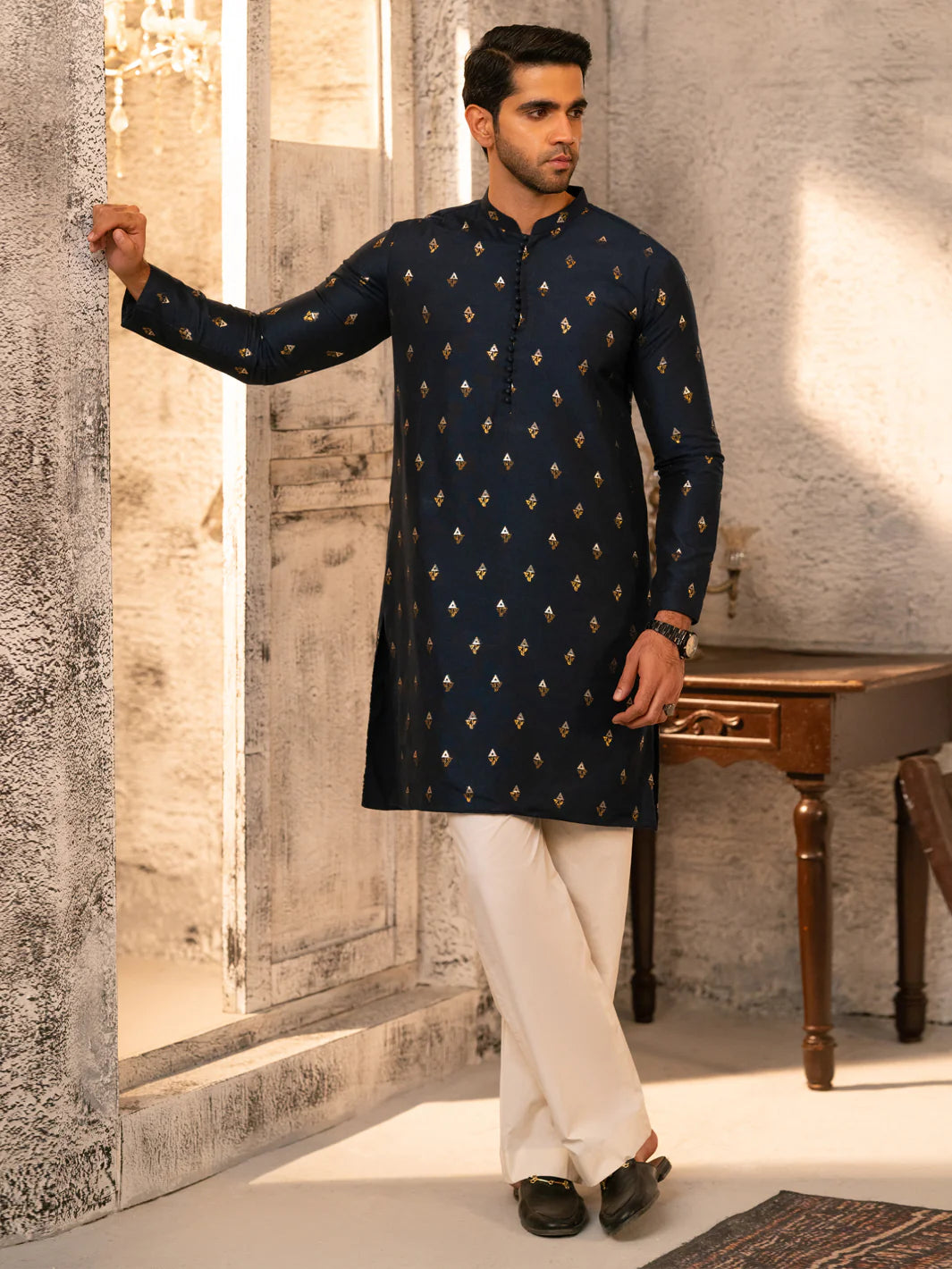 Navy blue ALMIRAH Formal Brocade Kurta AL-K-SP-071-16 with gold motifs, styled with white trousers for elegant winter fashion.