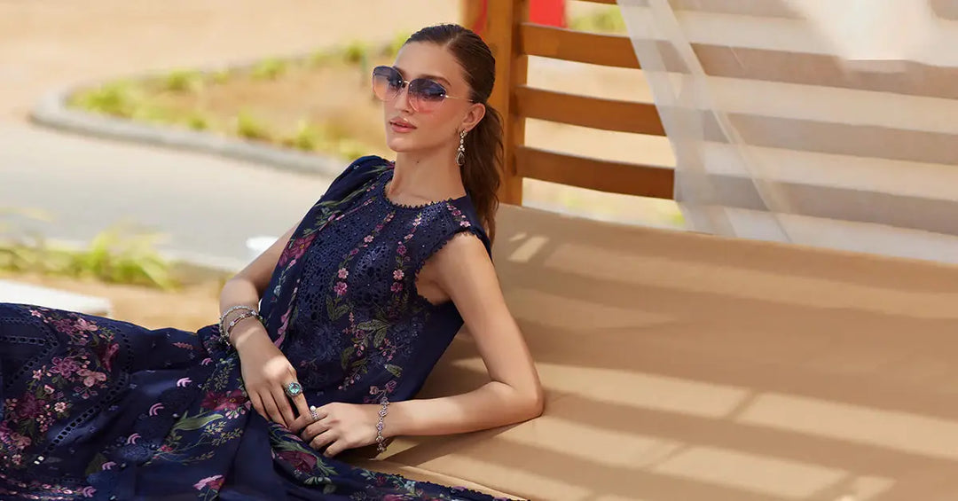 Model lounging in embroidered lawn suit AL-4311, featuring navy floral shirt and silk dupatta, perfect for elegant summer gatherings.