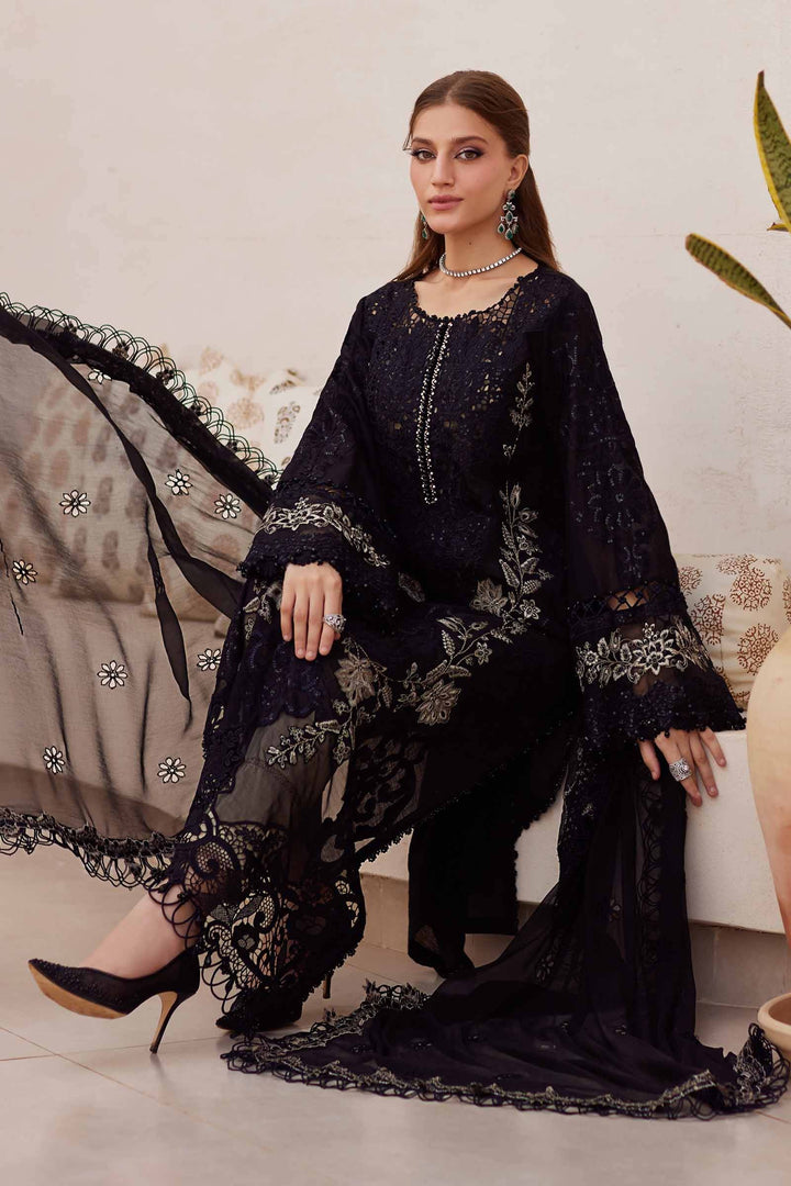 Model seated in AL-4312 black embroidered 3 piece suit with flowing chiffon dupatta and cambric trousers, styled for formal events.