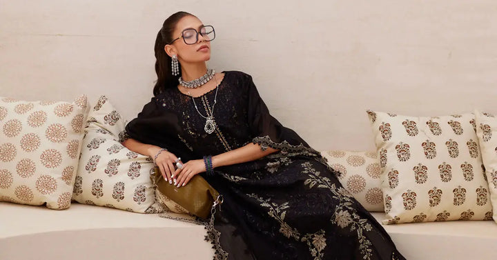 Model lounging in AL-4312 embroidered black 3 piece suit with statement jewelry, highlighting luxurious fabric and intricate design.