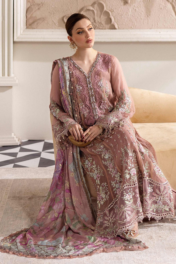 Seated model in MARIA.B MPC-25-105 embroidered chiffon suit featuring pastel floral motifs and organza accents for formal wear.