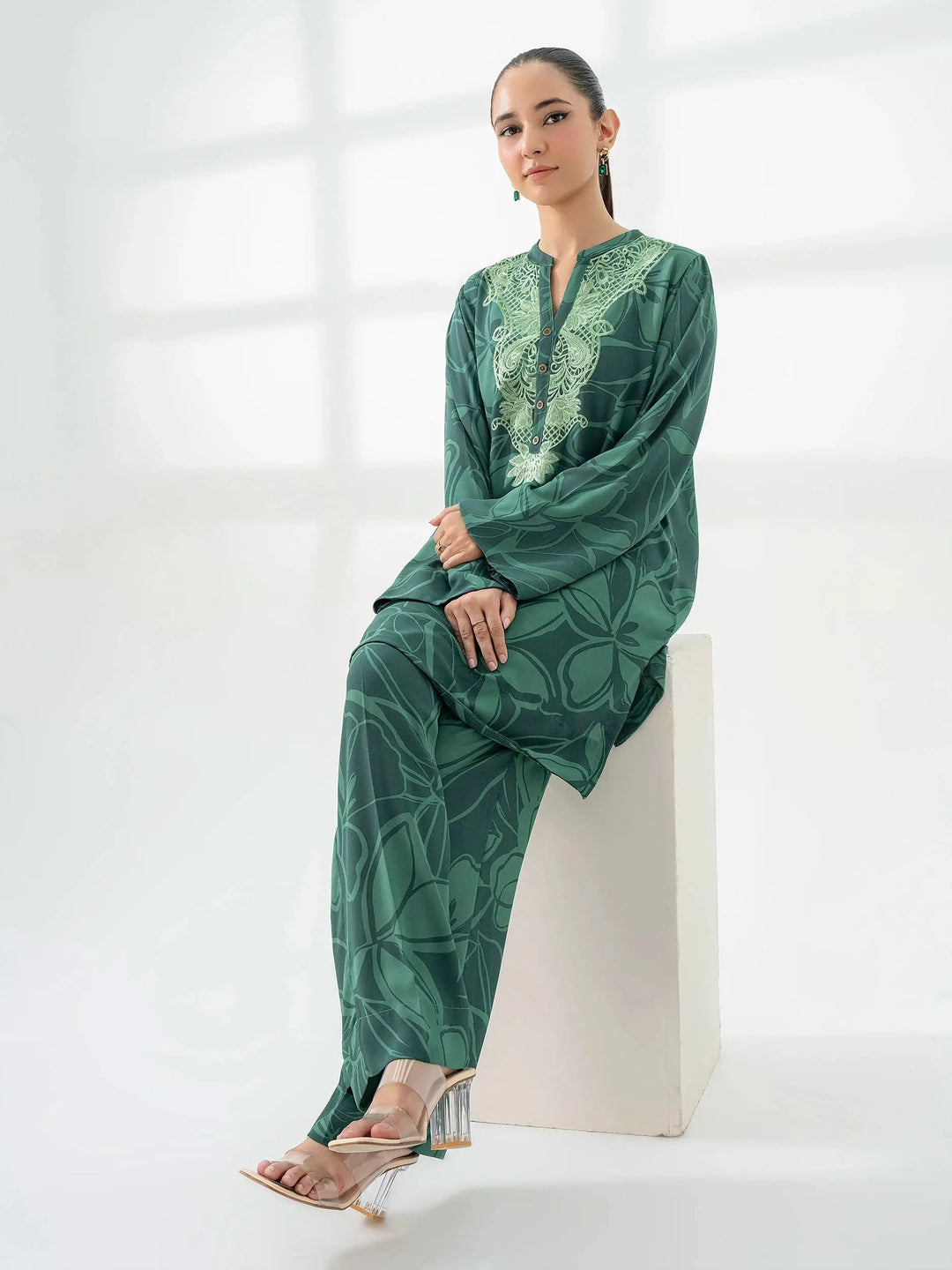 Model seated wearing Limelight's green printed co-ord set with floral patterns and embroidered neckline, styled with heels.