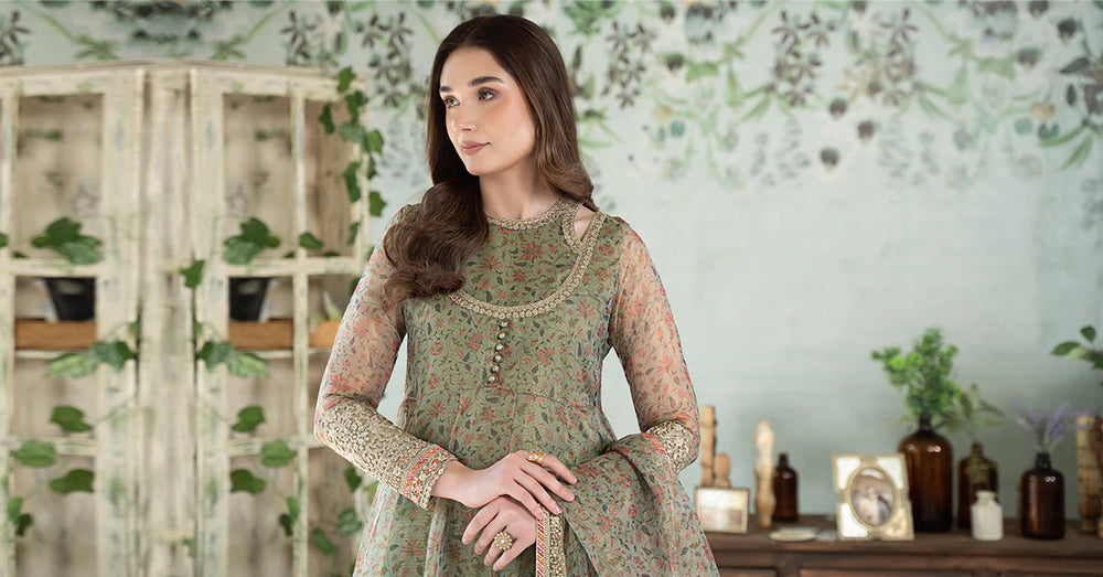 a MARIA.B woman in a green dress standing in front of a wall