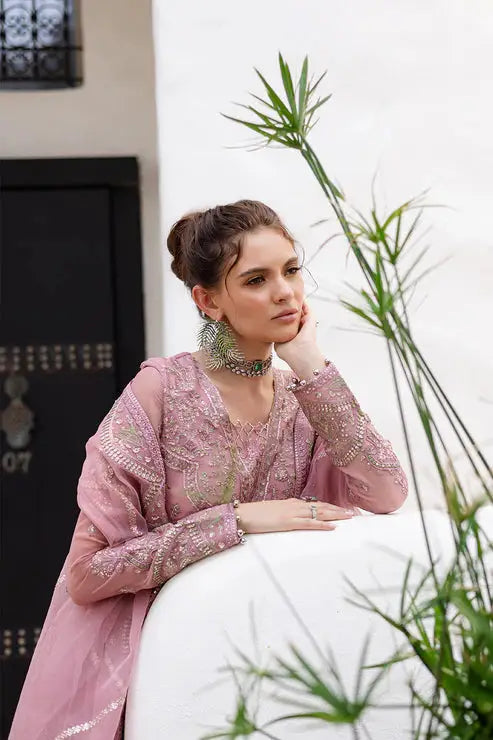 Model in MARYUM AND MARIA chiffon dress leaning on wall, showcasing detailed neckline embroidery and traditional Pakistani design elegance.