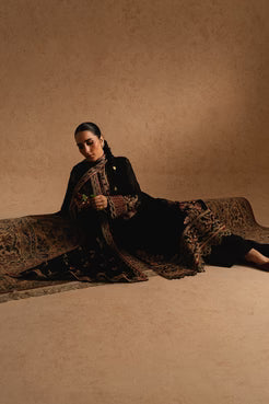 Model reclining in Maryum & Maria Chiffon ZEYNEB embroidered 3-piece black outfit, showcasing luxurious Pakistani chiffon fashion for women.