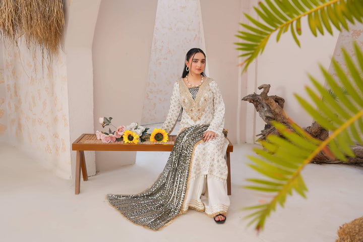 Model seated in RANGREZA SAJNI festive dress with floral decor, showcasing full outfit including shirt, pants, and dupatta.