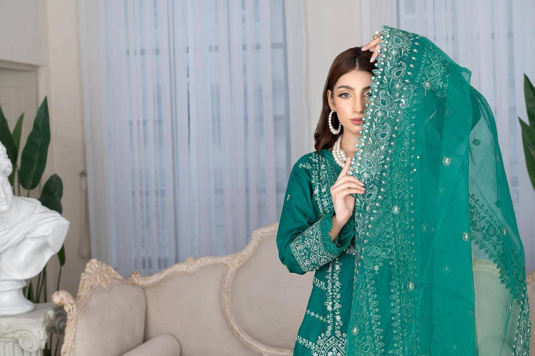 Model partially covering face with embroidered dupatta from Rangreza Sajni green lawn outfit, showcasing traditional Pakistani elegance.