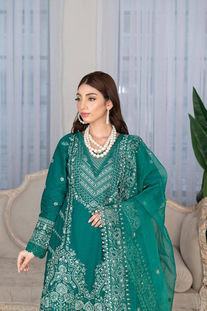 Close-up of Rangreza Sajni green embroidered shirt with pearl jewelry, highlighting detailed neckline and sleeve patterns.