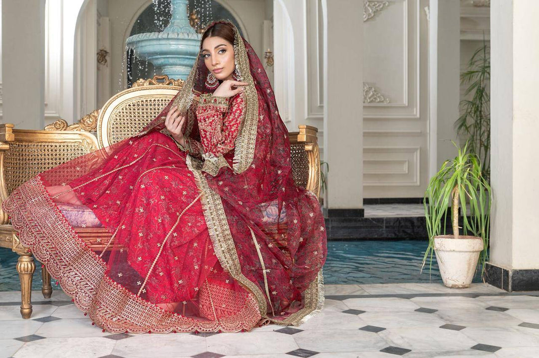 Model seated in RANGREZA SAJNI - Pakistani Outfits | Pink Long Frock Set with flared hem and ornate dupatta, ideal for ceremonial and festive occasions.