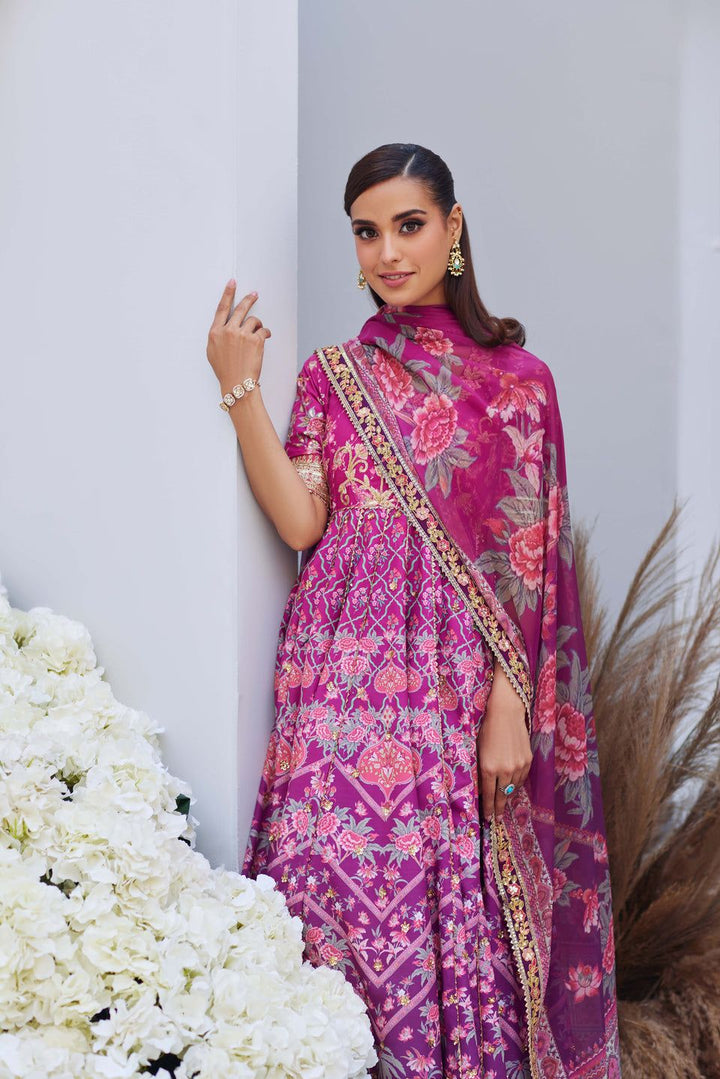 Mina Hasan pink printed and embroidered shirt with dupatta, model leaning against a white wall surrounded by floral decor.