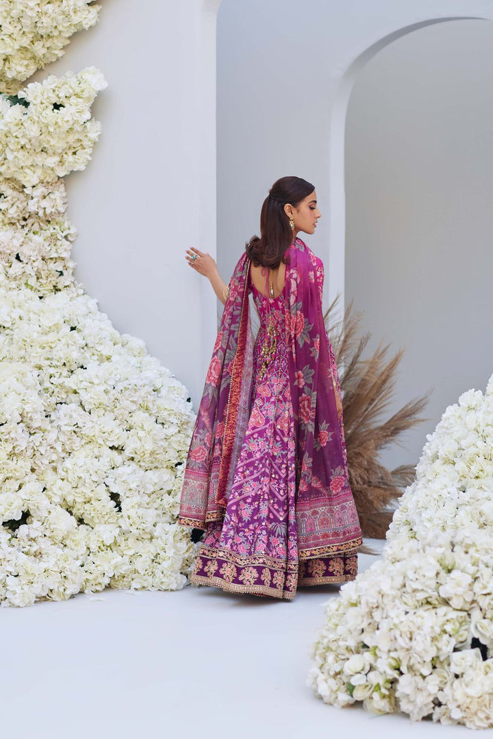 Back view of Mina Hasan pink embroidered shirt and dupatta with floral motifs, model walking away in a white floral setting.