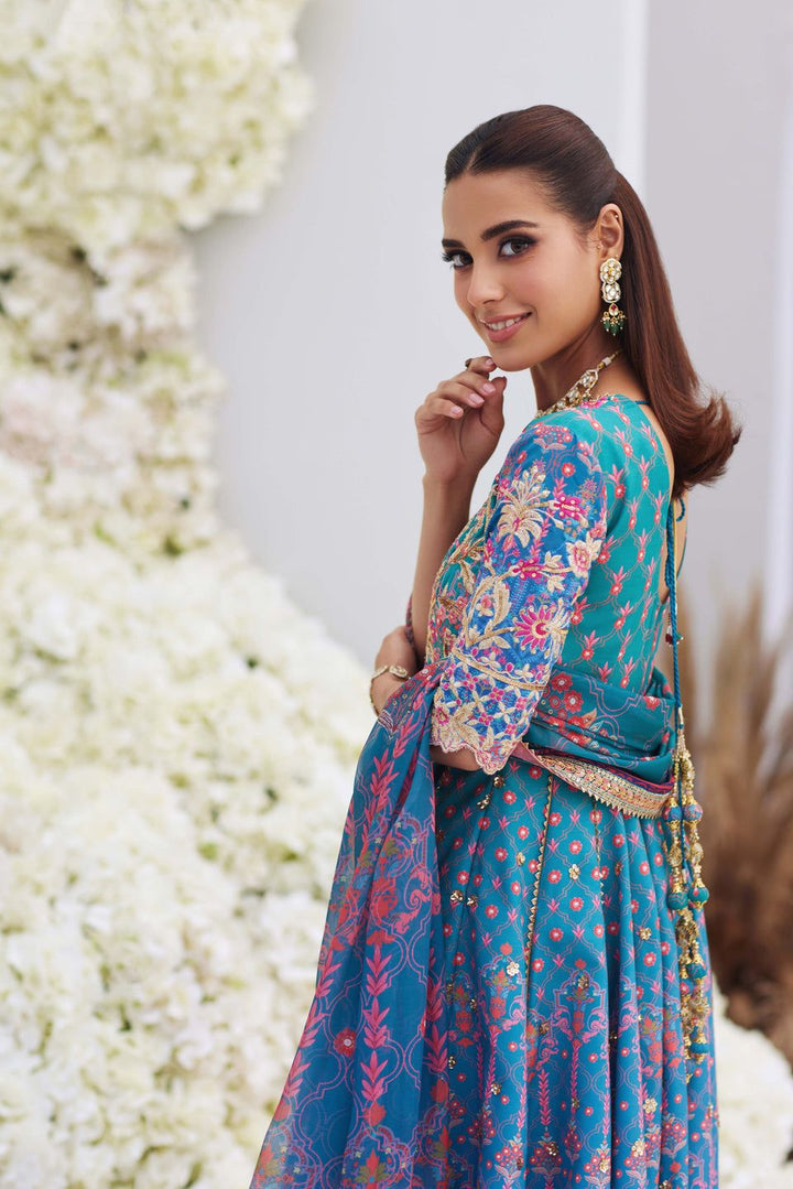 Side view of Mina Hasan blue embroidered shirt with floral patterns and tassel back, styled with gold earrings and bracelet.