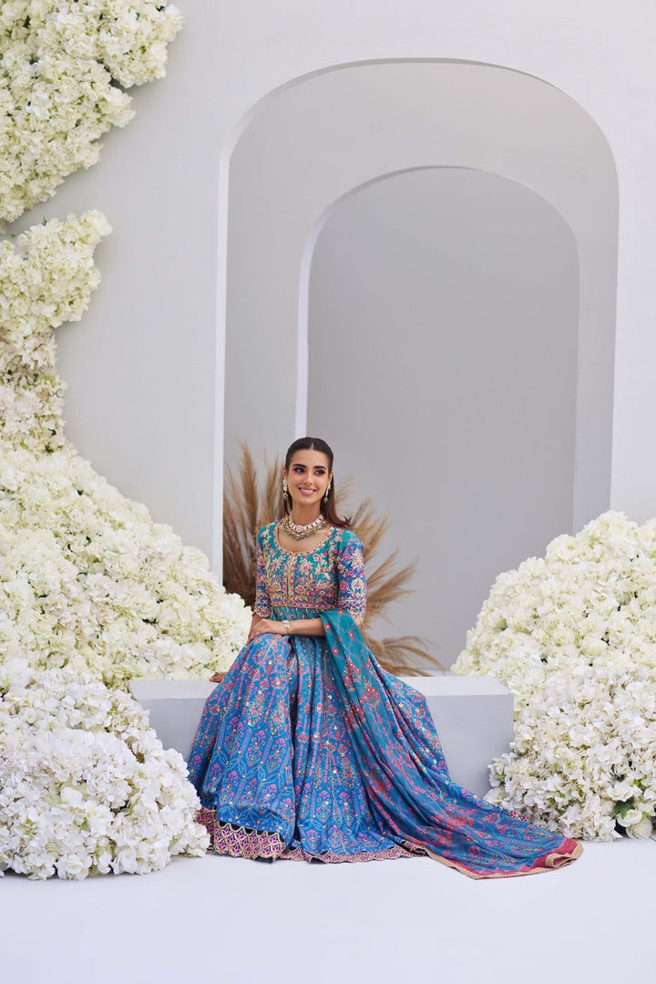 Mina Hasan blue ombre embroidered shirt and dupatta set, model seated among white flowers in a regal pose.
