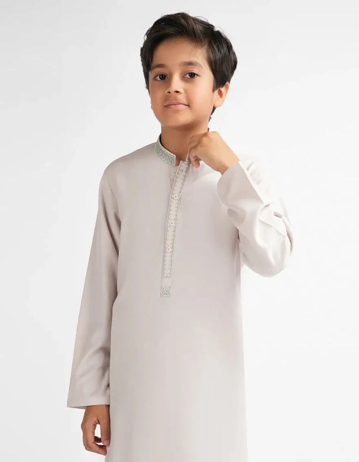 Young boy wearing a light gray kurta with white details on a white background