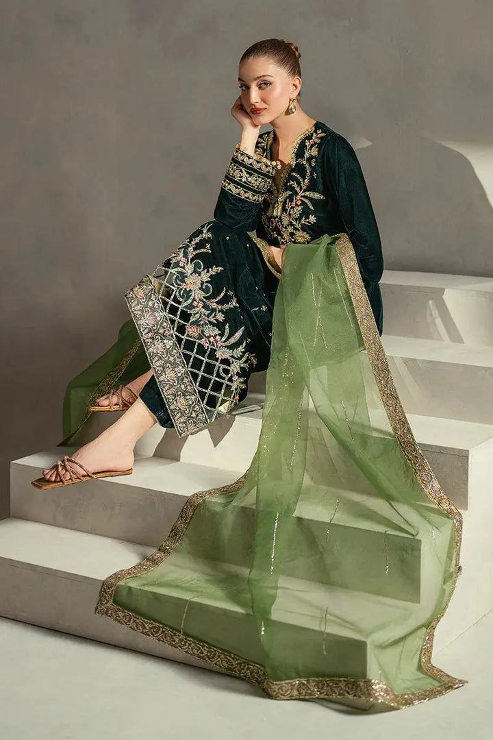 Model seated in MUSHQ Ayren green velvet embroidered outfit with gold-accented dupatta, perfect for festive and formal occasions.