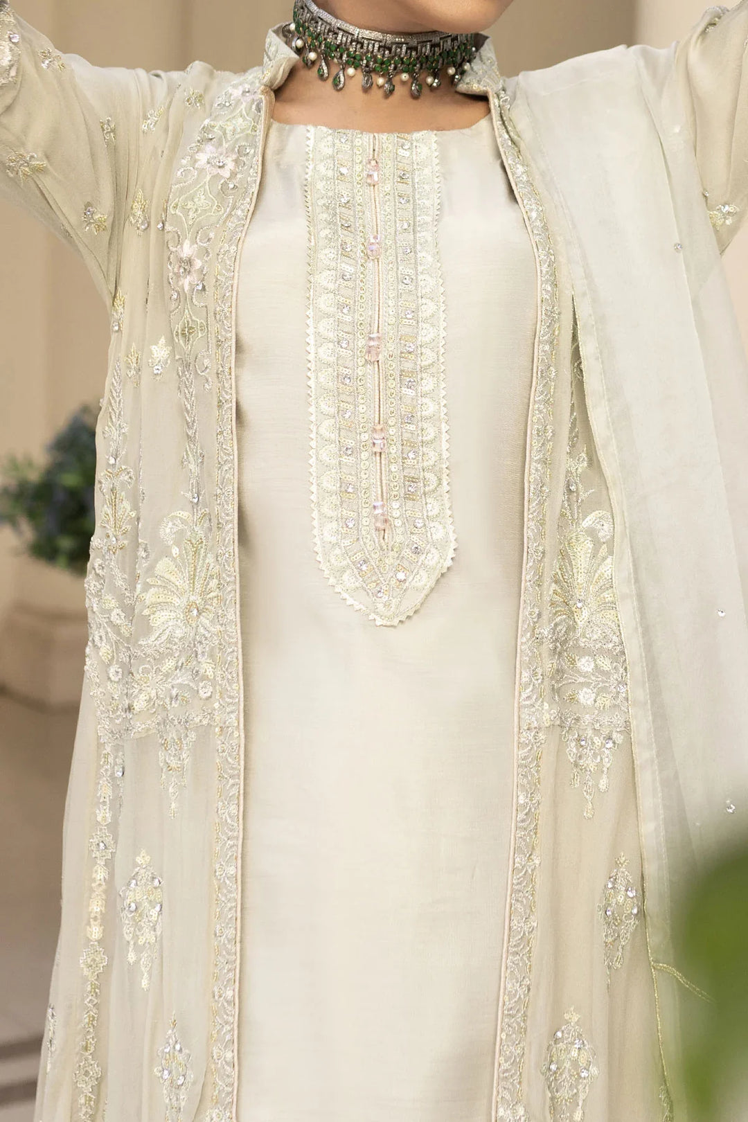Front embroidery detail of light grey Pakistan gown dress woman, featuring pearl and sequin embellishments for formal style.