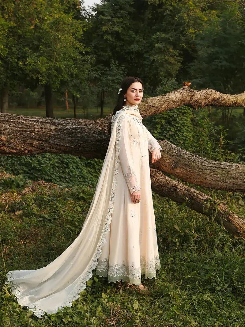 Full-length cream embroidered dress with dupatta, floral border, and lace, outdoor setting with trees