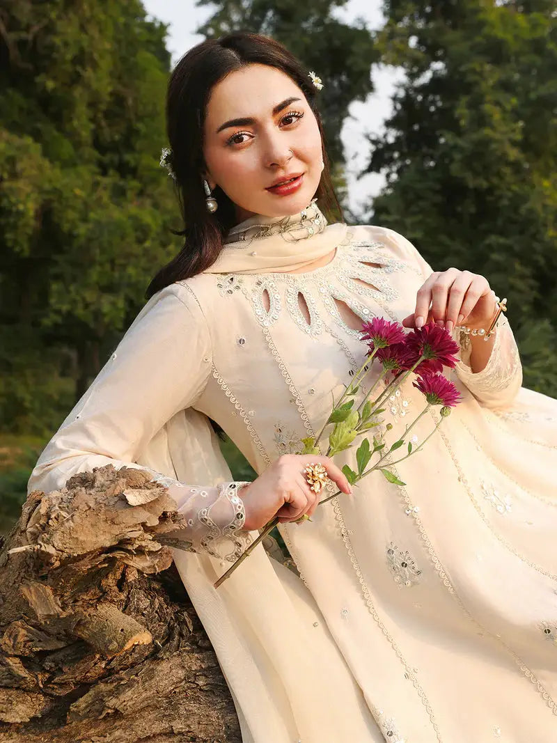 Model holding flowers in cream embroidered dress outdoors