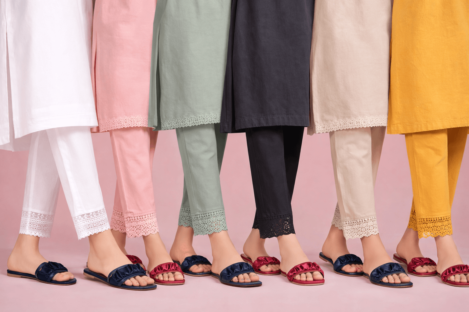 Colorful pants and shoes displayed against a pink background