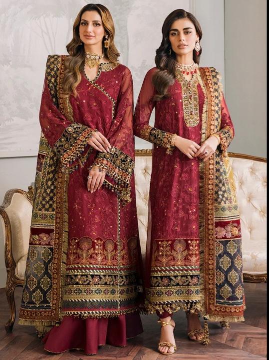 Two women wearing traditional embroidered outfits in a decorative room.