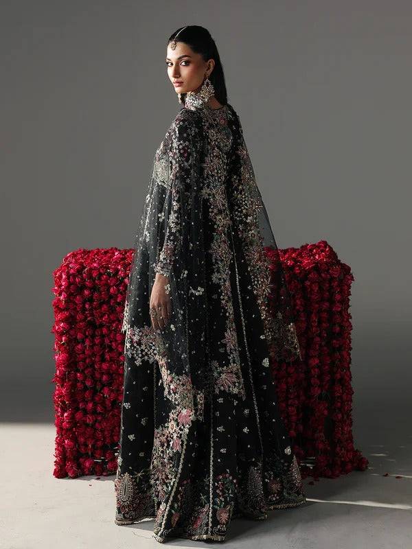 Back view of black embroidered dress with floral embroidery, model posing with floral backdrop