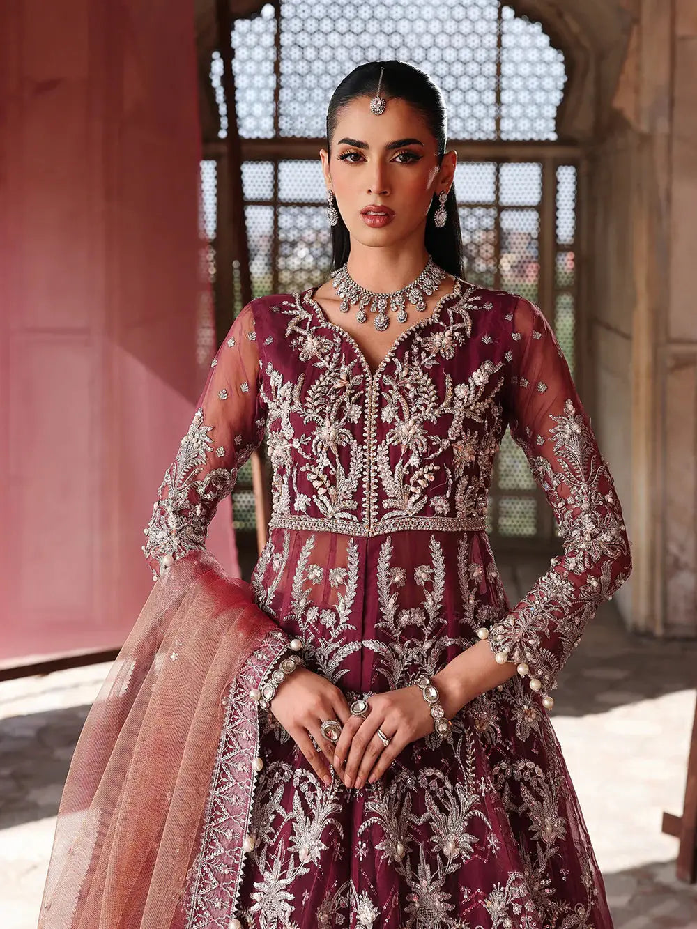 Maroon embroidered bridal dress with silver embellishments, jewelry, and sheer dupatta