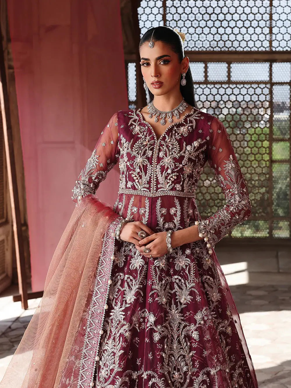 Model in maroon embroidered lehenga with silver jewelry and peach dupatta