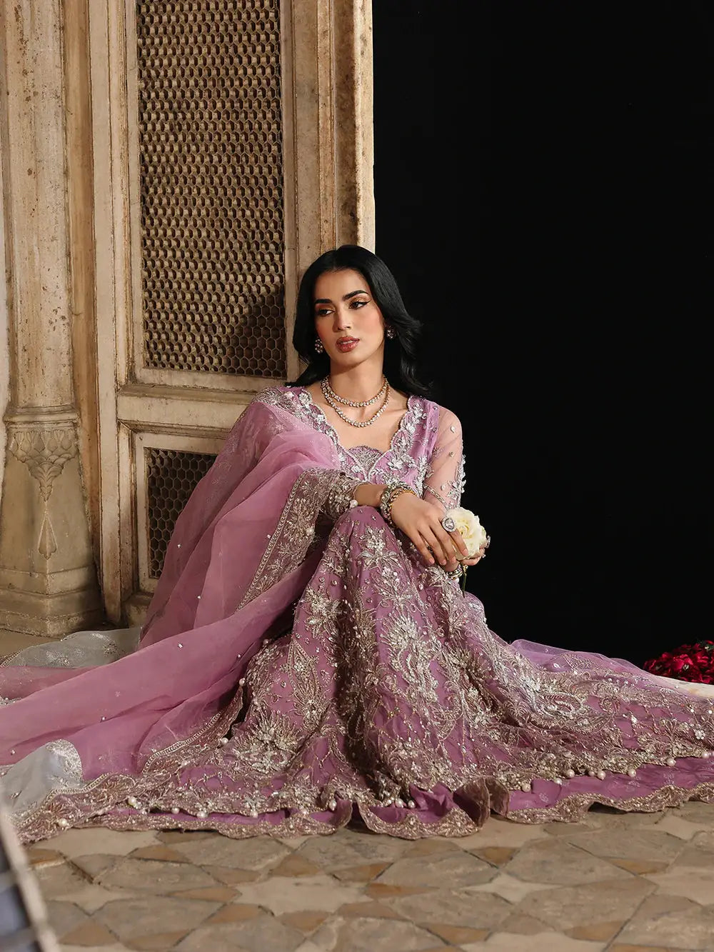 Pink embroidered traditional dress with jewelry and sitting pose