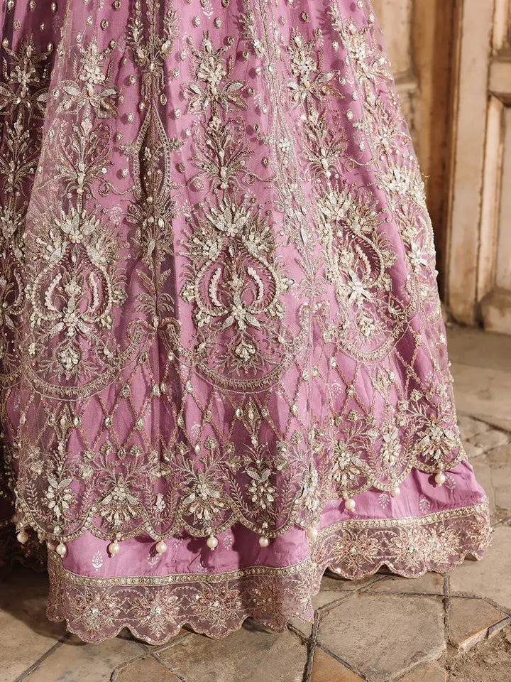 Detailed embroidery on pink dress with gold and silver thread, beads, and pearls, emphasizing craftsmanship and design