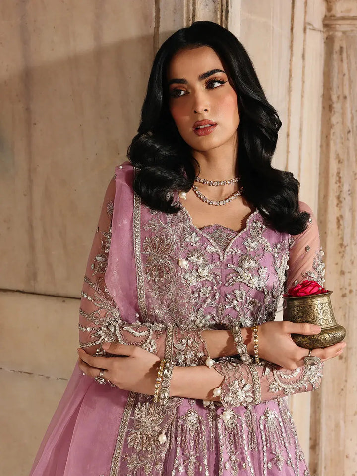 Pink embroidered traditional dress with jewelry and holding a flower