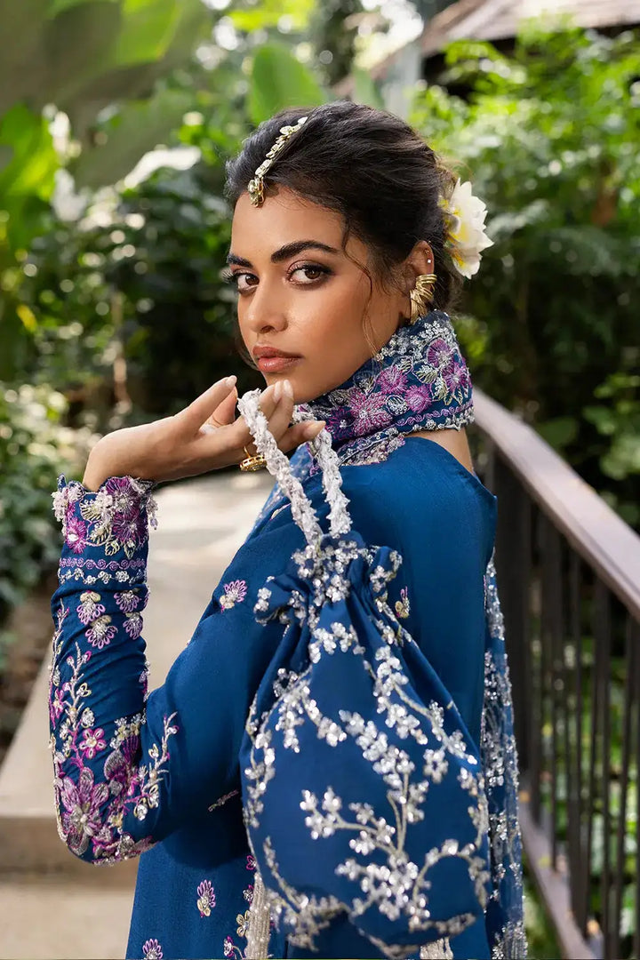 Detailed side profile of model in DELARA-SRF25-08 royal blue silk suit by SAIRA RIZWAN LUXURY, showing embellished sleeves and accessories.