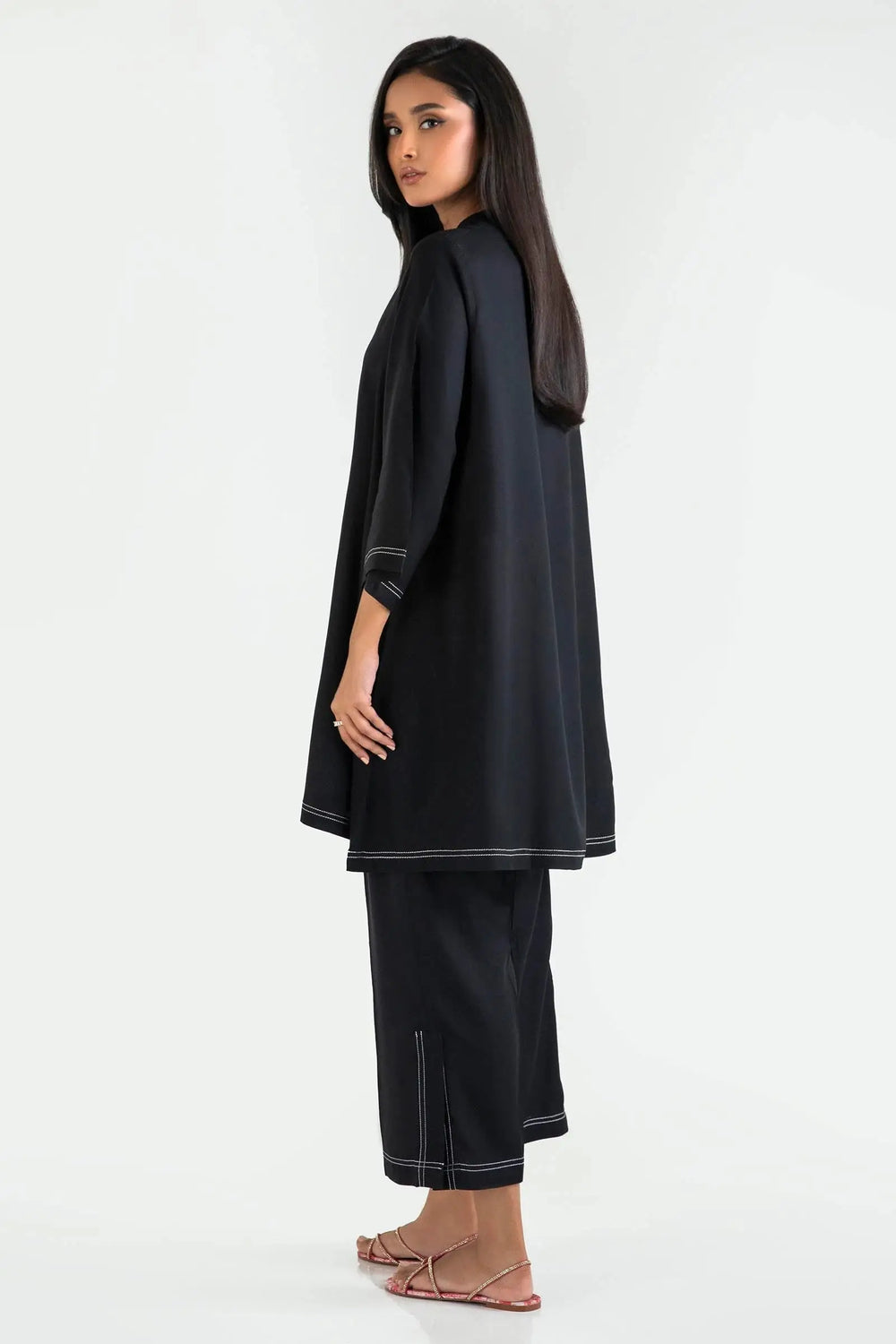 Woman wearing a black outfit with white trim on a white background