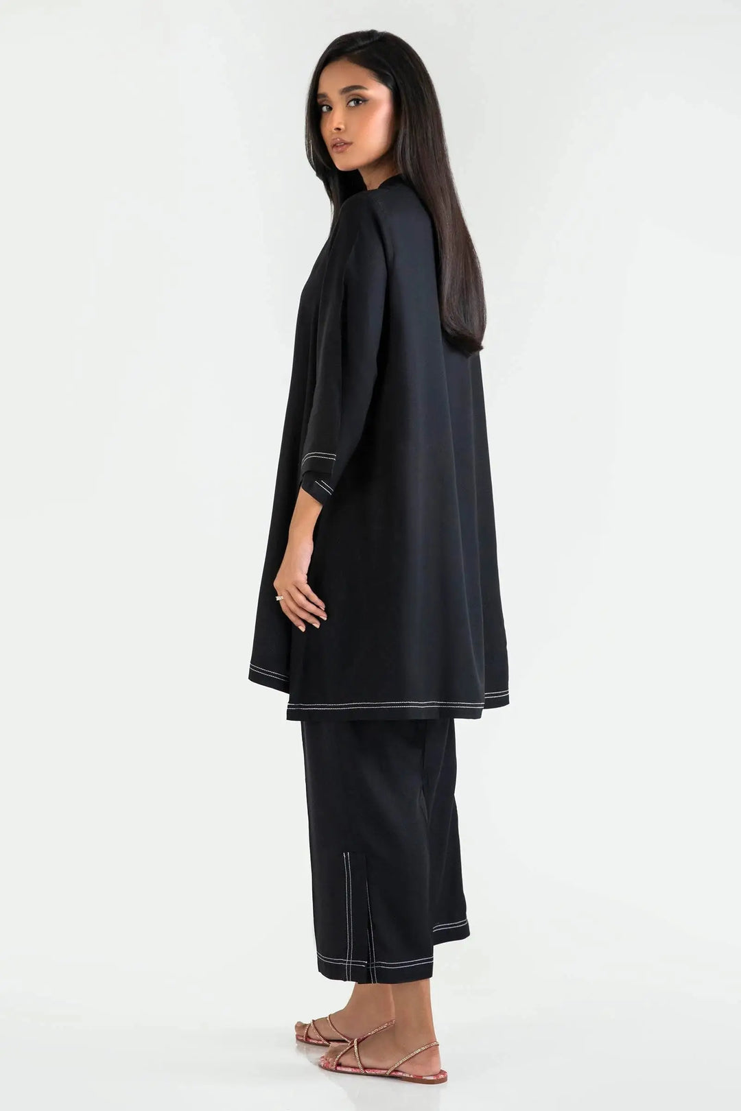 Woman wearing a black outfit with white trim on a white background