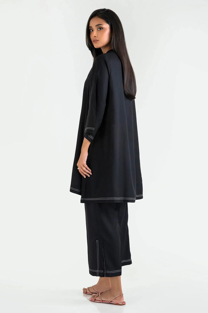 Woman wearing a black outfit with white trim on a white background