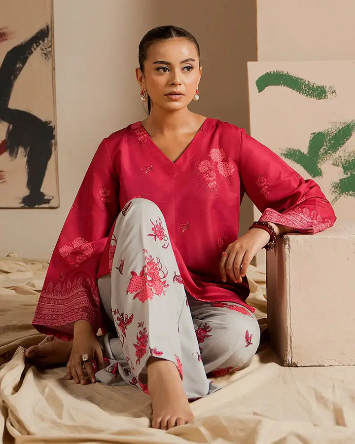 Stylish 2 Piece Outfit EA-24 with a printed raw silk co-ord set, showcasing a vibrant pink shirt and floral grey bottoms in a relaxed seated pose.