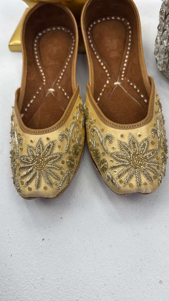 Close-up of Raeesa Golden Jutti showcasing ornate gold floral beadwork and classic khussa craftsmanship in traditional flat design.